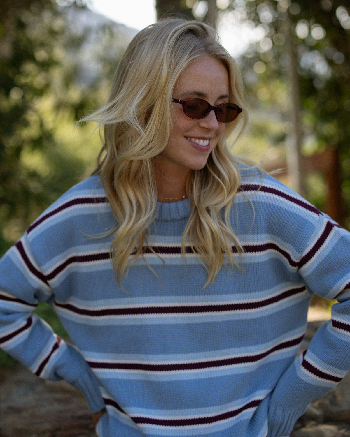 Smiling woman in a blue striped sweater wearing ETC sunglasses outdoors