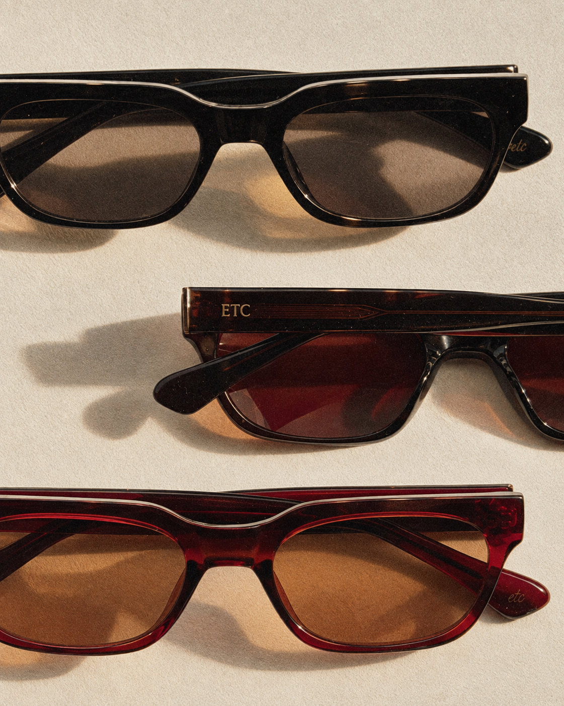 Three pairs of ETC sunglasses in Black, Brown and Cola laid flat